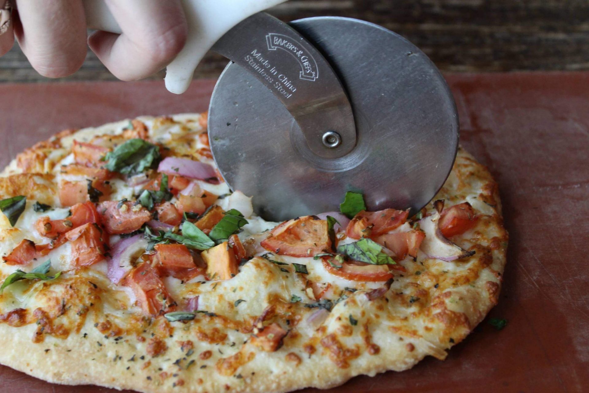 Pizza cutter slicing a pizza